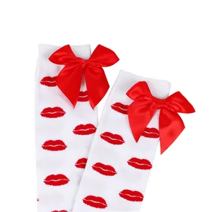 Detailed view of white over-the-knee socks featuring red lip prints and satin bows