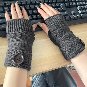 Détail des mitaines en tricot gris foncé avec boutons lors de la frappe sur un clavier
