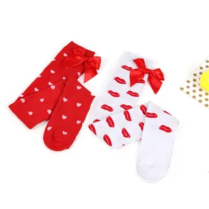 Close-up detail of Valentine's Day over-the-knee socks with red lip patterns and satin bows