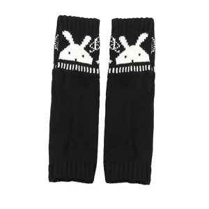 Detail van zwarte gebreide vingerloze armwarmers met een wit konijnenpatroon ontwerp.