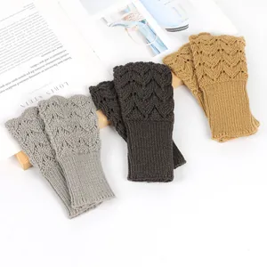 Close-up of knitted fingerless gloves with hollow heart patterns in three colors.