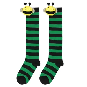 Close-up view of children's green and black striped socks with cute bee plush toy.