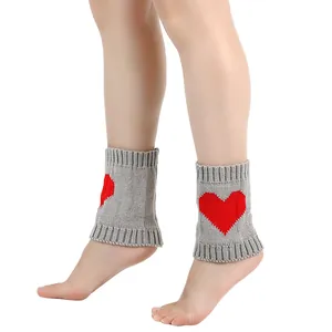 Gedetailleerd overzicht van grijze gebreide beenwarmers met een rood hartpatroon