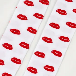 Close-up of vibrant red lip prints on white knitted over-the-knee socks for Valentine's.