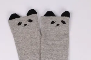 Detailed view of cute grey panda socks with 3D black pom-pom ears and cartoon face