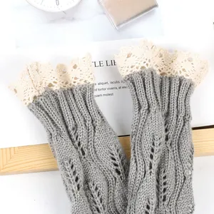 Close-up of grey knitted fingerless gloves with elegant cream lace trim and leaf pattern.