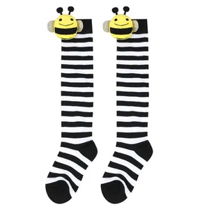 Close-up of striped children's knee-high socks featuring a cute plush bee doll detail.