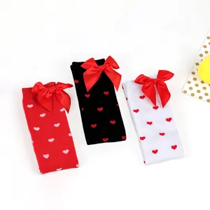 Detail view of heart pattern over-the-knee socks with large red satin bows in three colors
