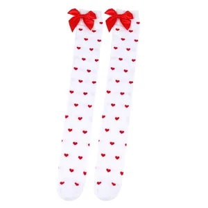 Detailed view of white over-the-knee socks featuring red hearts and satin bows.