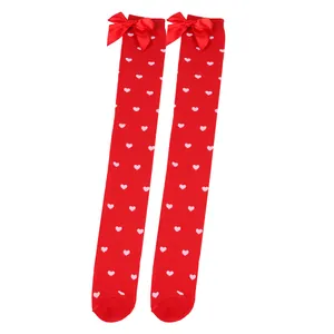Detail view of red over-the-knee socks with pink heart patterns and red bows