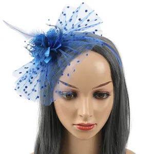 Close-up detail of a blue fascinator headband featuring feathers and a polka dot mesh veil.