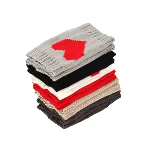 Stapel kleurrijke dikke gebreide beenwarmers met een rood hartjespatroon voor laarzen.
