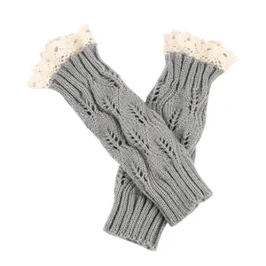 Detail view of grey knitted fingerless gloves featuring hollow leaf pattern and white lace trim