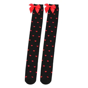 Black over-the-knee socks with red heart patterns and satin bows for Valentine's Day.