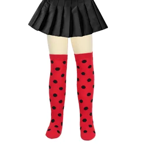 Detail view of children's ladybug themed red socks with black polka dots on mannequin legs.
