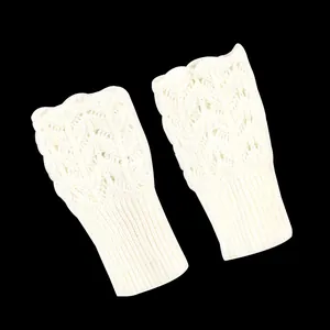 Close-up of white knitted fingerless gloves with hollow heart pattern detailing.