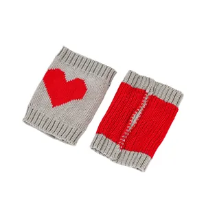 Detailopname van grofgebreide beenwarmers met een rood hartpatroon op grijs en rood garen.