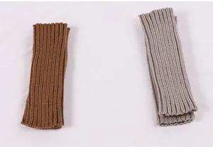 Two pairs of knitted acrylic arm warmers in brown and grey shown side by side.