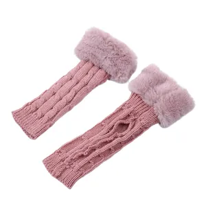 Detail of pink cable-knit fingerless gloves with soft faux fur cuffs and thumb hole