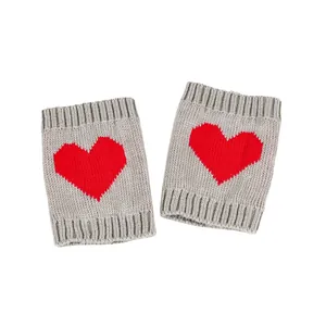 Detailweergave van grijze gebreide beenwarmers met een rood hart jacquard patroon
