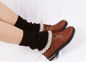 Detailed shot of dark brown knitted leg warmers with elegant cream lace trim on boots