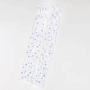 Dettaglio di guanti lunghi a rete bianchi decorati con strass scintillanti per feste.
