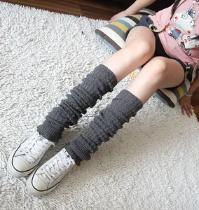 Detailed view of cozy gray knitted leg warmers worn with white canvas sneakers