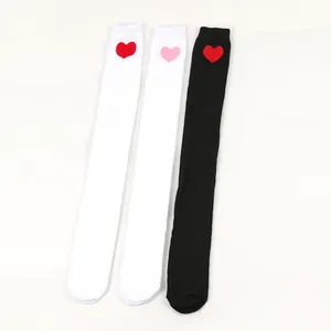 Detailed view of three over-the-knee socks with heart patterns in white and black