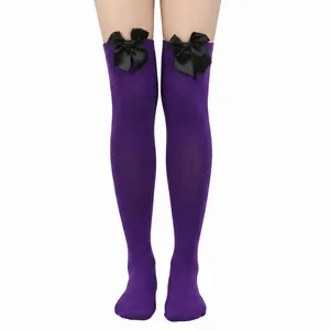 Detalle de calcetines altos morados con elegantes lazos de satén negro arriba