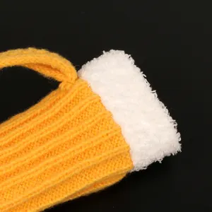 Close-up of yellow knitted yarn and white plush trim on beer mug themed winter mitten