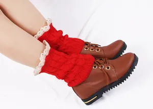 Detail shot of red knitted leg warmers with white lace trim paired with brown leather boots