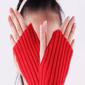 Detailed close-up of vibrant red knitted fingerless gloves with ribbed texture in use