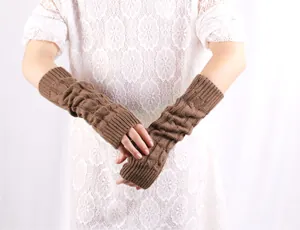 Close-up detail of brown cable knit long fingerless arm warmers on model's arms