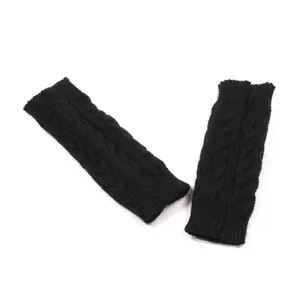 Detail van zwarte kabelgebreide vingerloze armwarmers voor warmte in de herfst en winter