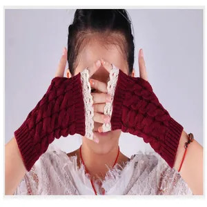 Gros plan de mitaines en tricot torsadé bordeaux avec dentelle blanche sur un modèle.