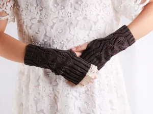 Detail view of brown cable knit fingerless gloves with delicate lace trim on model.