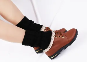 Detailed view of black cable knit leg warmers with elegant cream lace trim on brown boots.