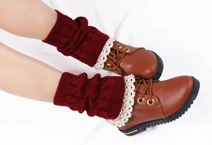 Close-up of wine red knitted leg warmers with delicate white lace trim on boots