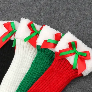 Close-up of festive knitted leg warmers with plush trim and red-green layered bows