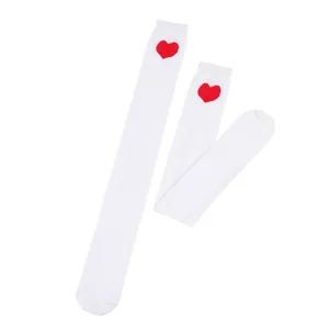 Detail of white over-the-knee socks featuring a red heart motif near the cuff