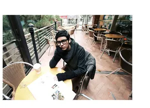 Detail of male model wearing dark grey cable knit fingerless arm warmers in a cafe setting