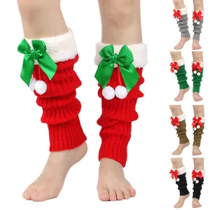 Detailed view of knitted Christmas leg warmers with a festive bowknot and plush pom-poms