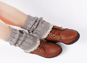 Close-up of grey knitted leg warmers with delicate lace trim and cable knit pattern