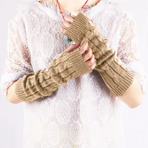 Close-up detail of khaki cable knit fingerless arm warmers on white lace top.