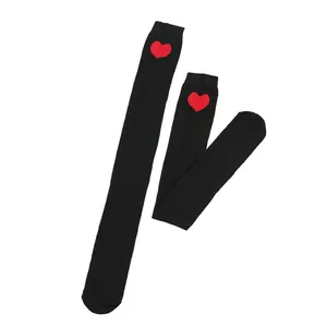 Detail of black thigh-high socks featuring a vibrant red heart pattern at the top