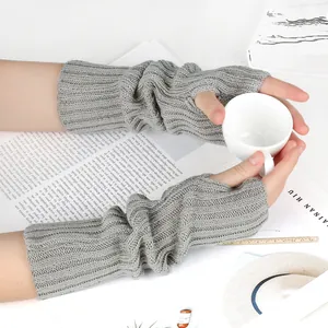 Cozy grey knitted fingerless arm warmers with thumb holes in a minimal lifestyle setting.