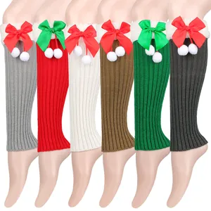 Selection of festive knit leg warmers with decorative bows and pom-poms in various colors