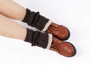 Close-up detail of brown knit leg warmers with delicate lace trim over leather boots.