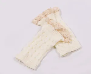 Detailed texture of white cable knit leg warmers with delicate lace trim edging.