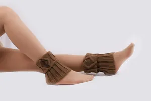 Detail brauner gestrickter Stiefelstulpen mit Knöpfen über einer hautfarbenen Strumpfhose.